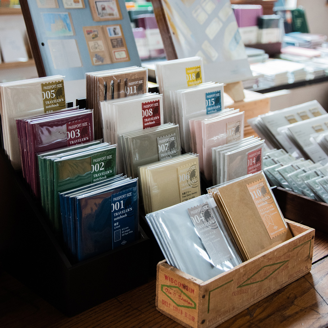 TRAVELER'S notebook in Passport Size displayed in wood containers.
