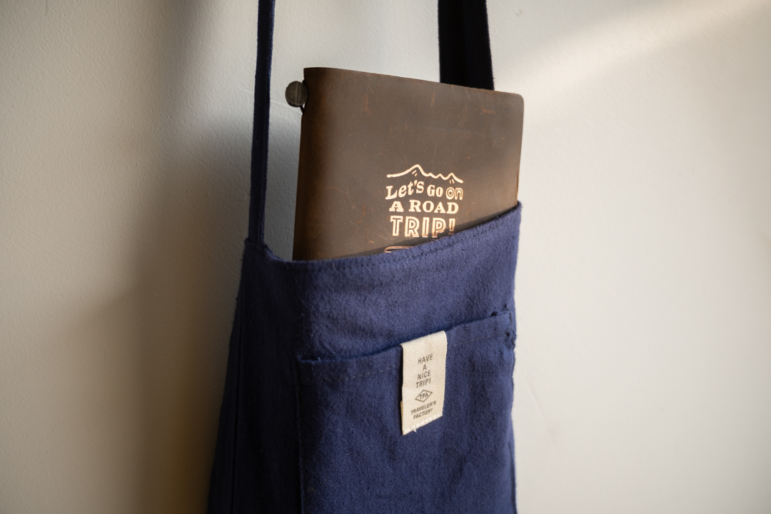 A TRAVELER'S notebook ROAD TRIP poking out of a navy sacoche.