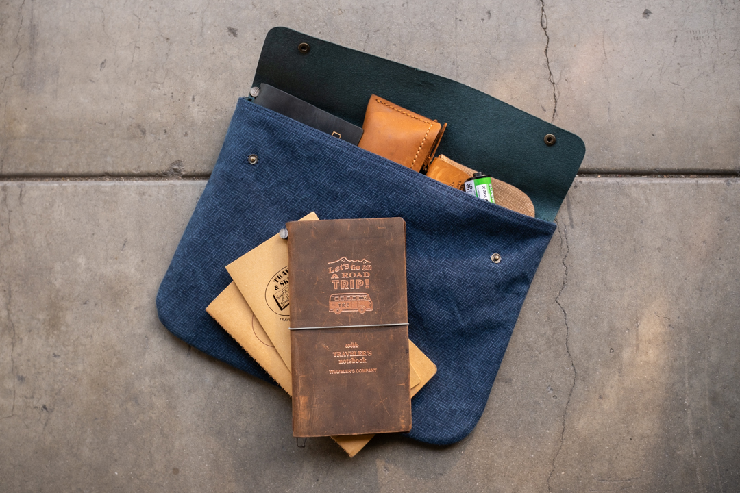 TRC USA Limited items including the ROAD TRIP TRAVELER'S notebook, TRAVEL & SKETCH, and other TF Original items are placed inside a large Canvas Pouch in blue.