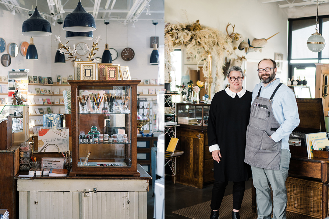 The interior of Paper and Grace stationery shop, with shop owner Jill and Cody stand amongst the shop's paper goods, stationery and beautiful vintage wooden decor, and dried flowers.