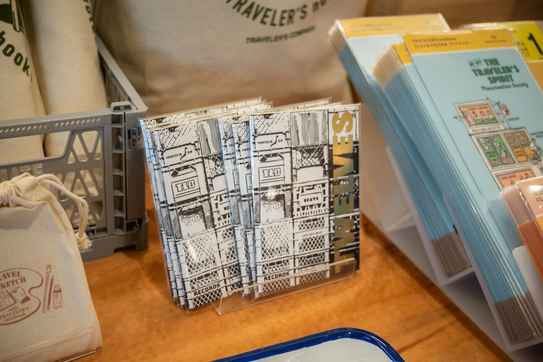 Two stacks of notebooks standing on a rack on a exhibitor table filled with TRAVELER'S COMPANY items and products.