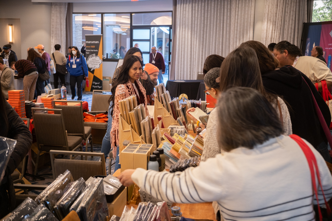 People shopping for notebooks and other stationery at TRAVELER'S COMPANY USA table at the California pen show.