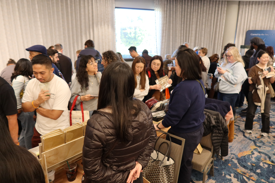 Crowds of people shopping for notebooks and other stationery at the TRAVELER'S COMPANY USA table at the California pen show.