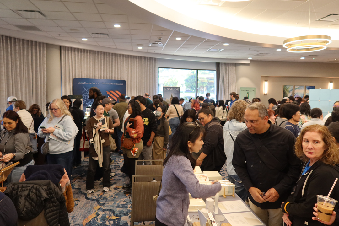 Crowds of people shopping for notebooks and other stationery at the TRAVELER'S COMPANY USA table at the California pen show.