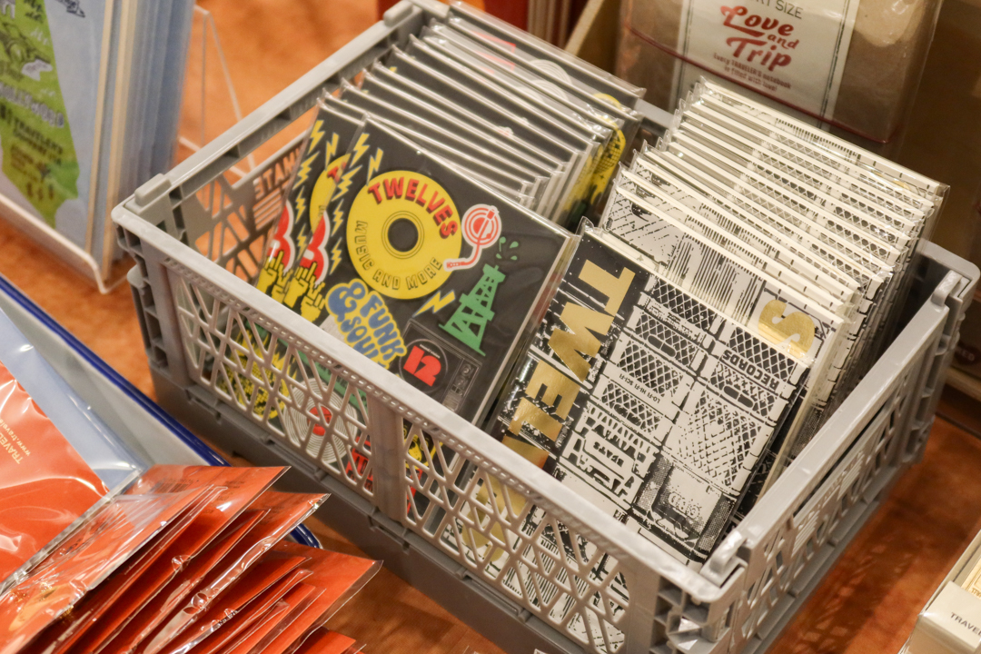 Two stacks of notebooks standing on a plastic crate on an exhibitor table filled with TRAVELER'S COMPANY items and products.