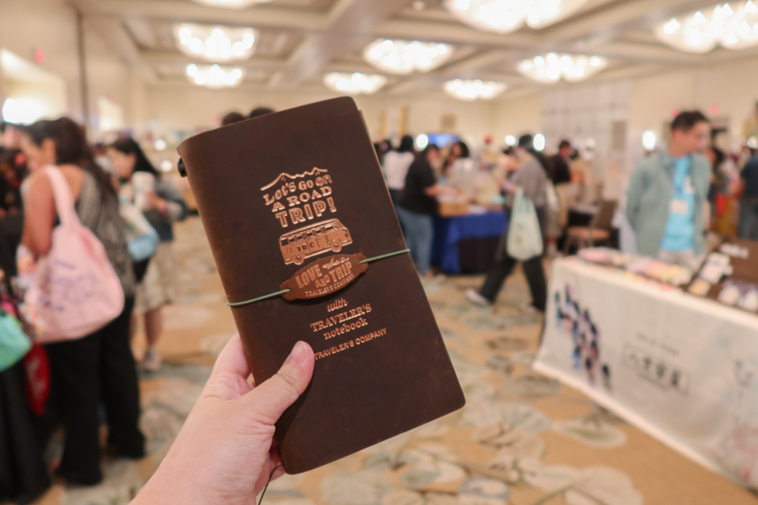 A person holding a Road Trip Edition TRAVELER'S notebook at the SF Stationery Festival.