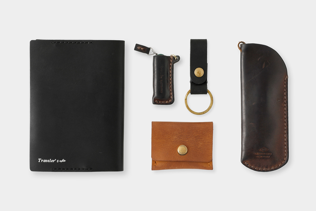 A variety of TRAVELER'S FACTORY leather goods like keychains, wallets, book covers and glasses cases, all worn and used with an evident leather patina.