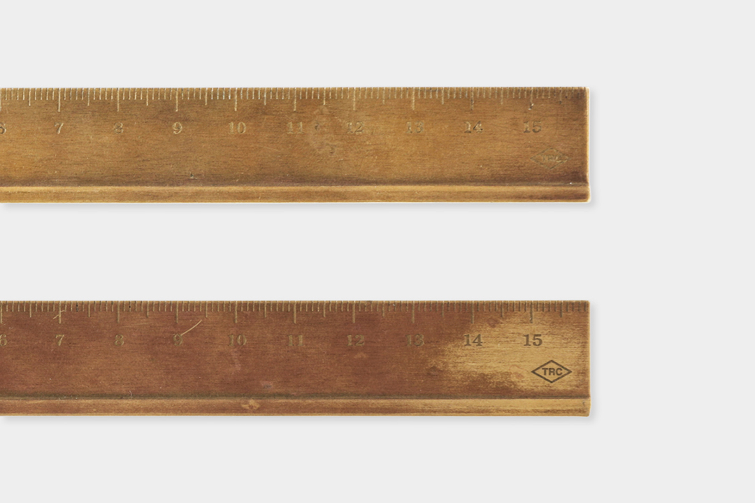 A new brass ruler beside a used brass ruler to showcase the patina and aging process of raw solid brass.