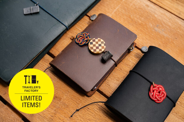 TRAVELER'S notebooks decorated with Tin, YOSEGI, and MIZUHIKI charms against a wooden table.