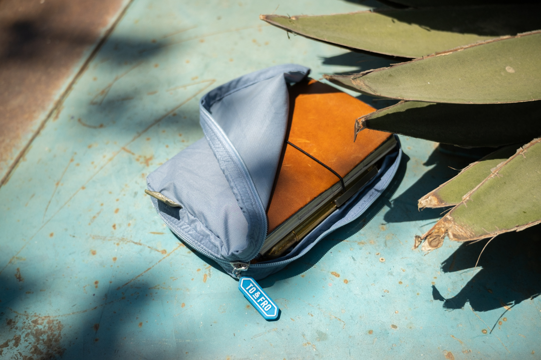 A TRAVELER'S notebook passport size in Camel inside a TF TO&FRO organizer in blue.