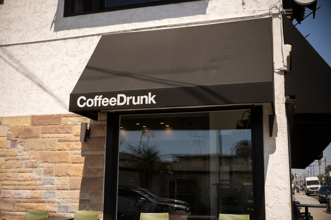 The exterior of the CoffeeDrunk coffee shop which has a black awning.