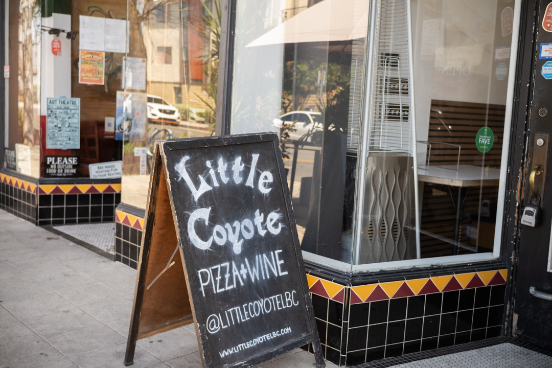 A chalkboard sign for Little Coyote pizza is displayed on the sidewalk on Retro Row, Long Beach, California.