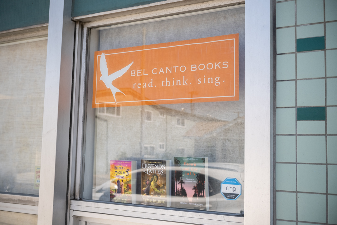 An orange sign logo containing a bird is displayed on the glass window of a building.