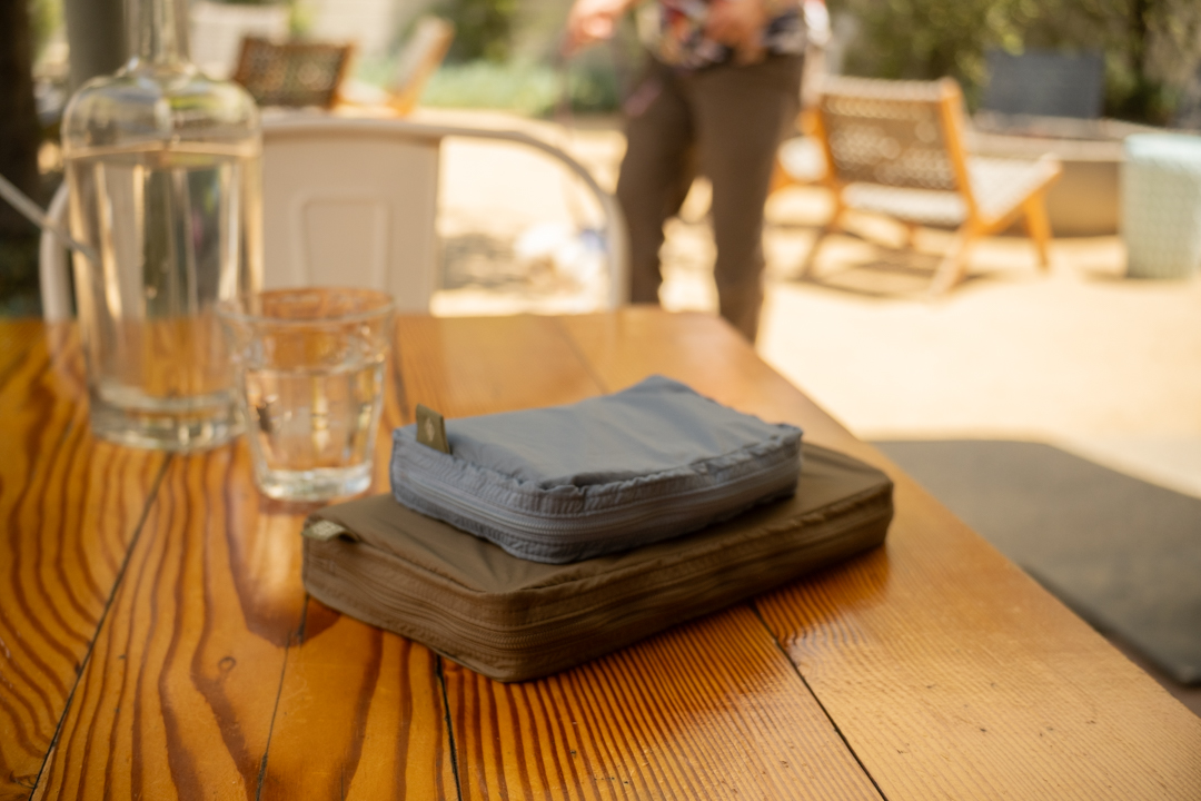 A wooden restaurant table with a TO&FRO organizer protecting the TRAVELER'S notebook.