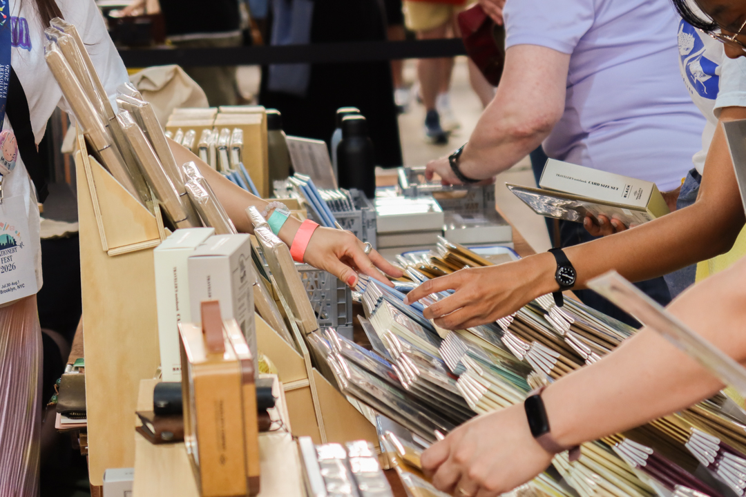 A person reaching for TRAVELER'S notebook inserts at the TRC USA table at Stationery Fest 2026.