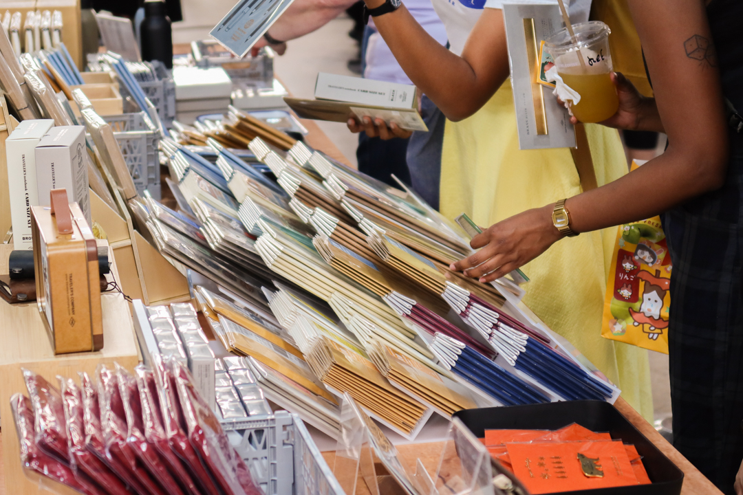 A person reaching for TRAVELER'S notebook inserts at the TRC USA table at Stationery Fest 2026.