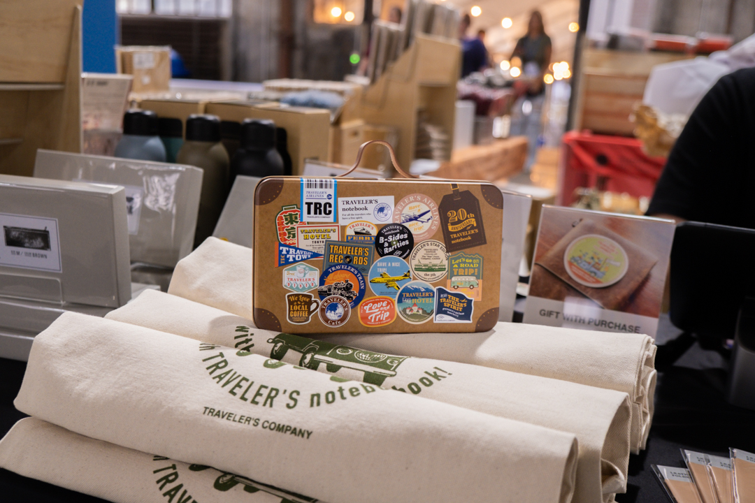 The TRC 20th Anniversary Tin resting on rolled up tote bags.