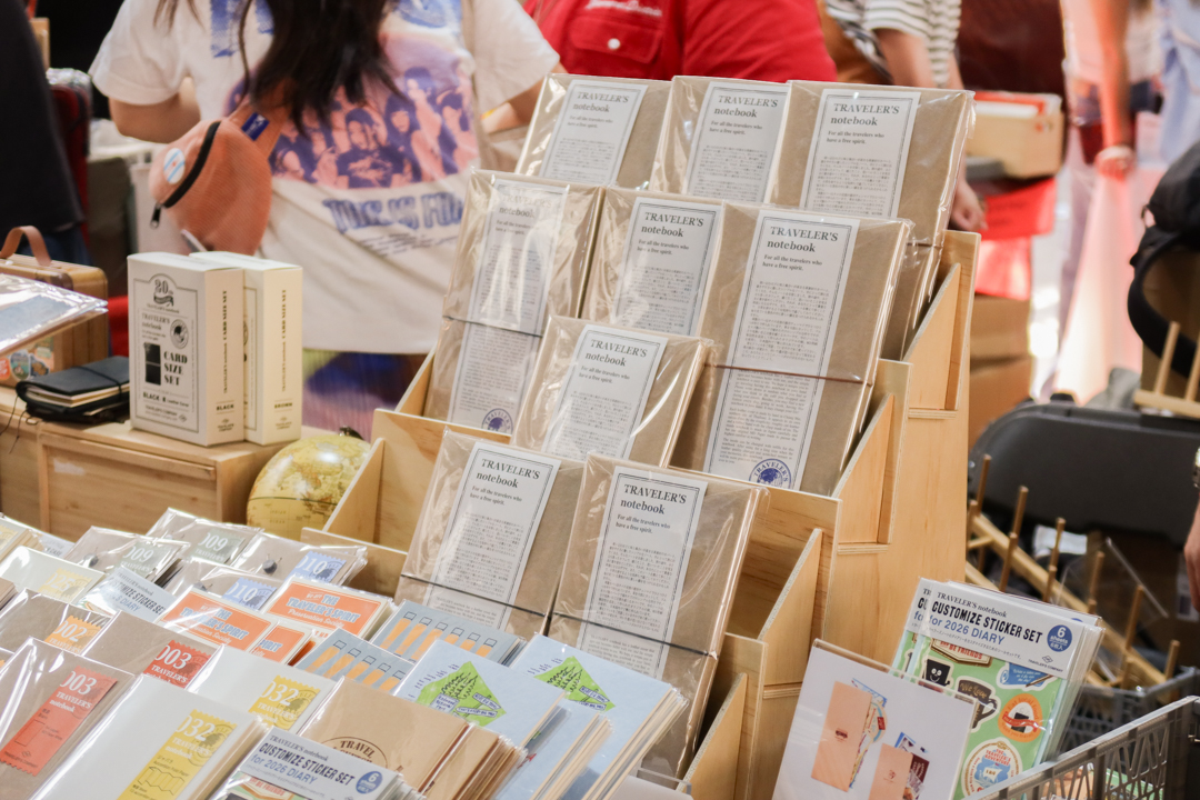 TRAVELER'S notebooks displayed on wooden rack with other TRAVELER'S notebook inserts on the TRC USA table at Stationery Fest 2026.