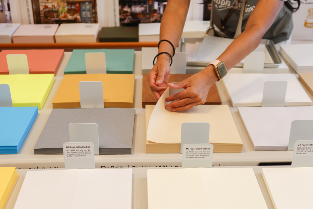 A hand flipping through the paper buffet at the DIY TRAVELER'S notebook! workshop.