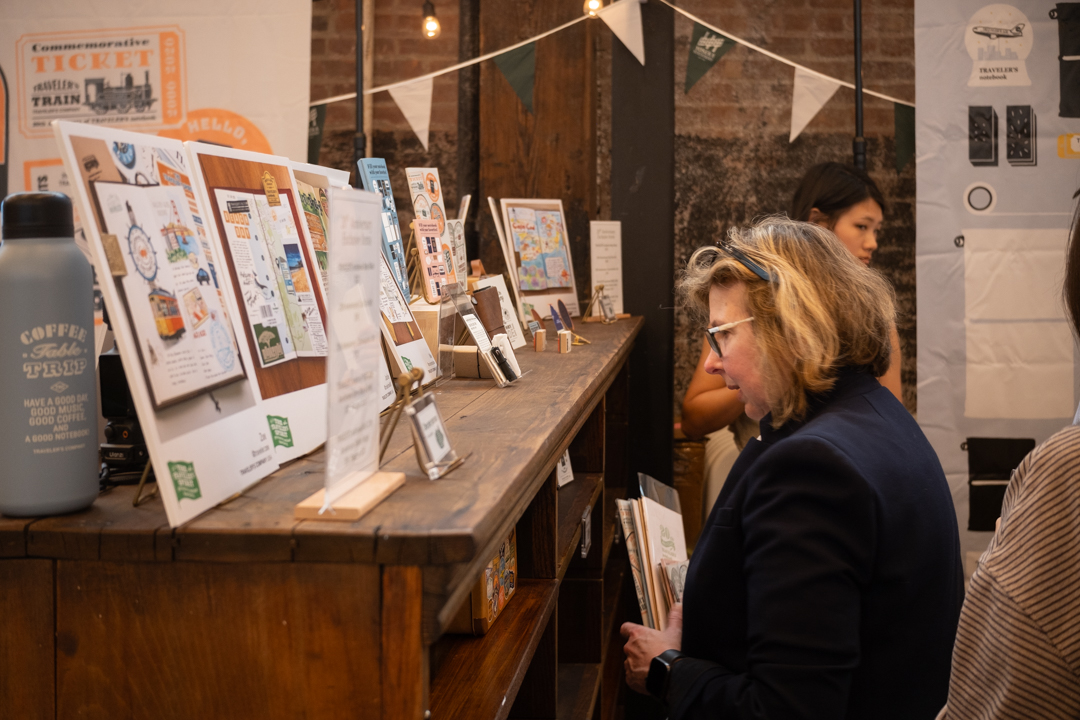 woman looking at TRAVELER'S COMPANY items and displays on a shelf.