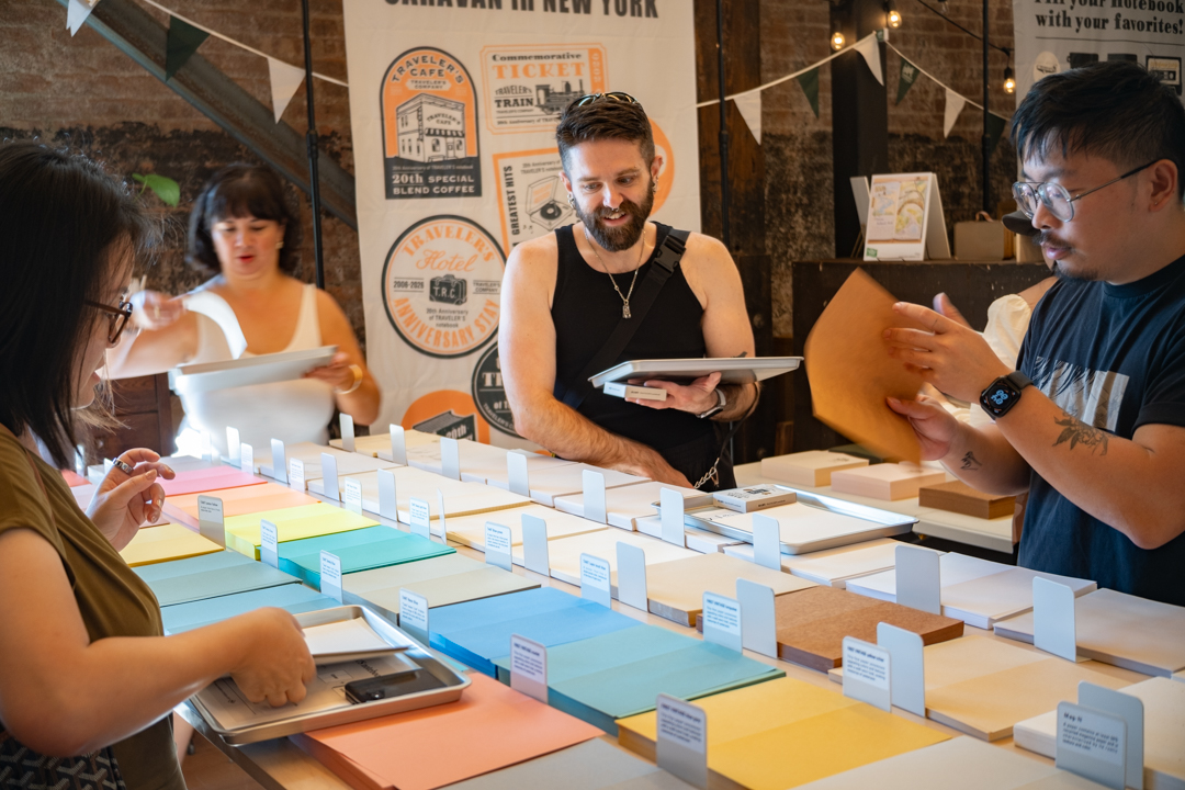 A gathering of TRAVELER'S notebook fans making their own refill by choosing papers from the table.