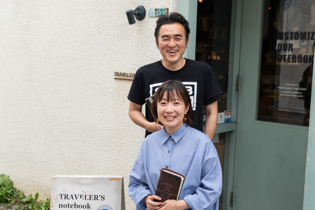 Miho and IIjima, the creators of TRAVELER'S notebook posing outside of TRAVELER'S FACTORY Nakamegeuro.