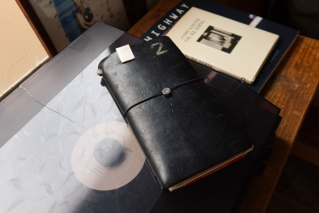 A black TRAVELER'S notebook resting on a book.